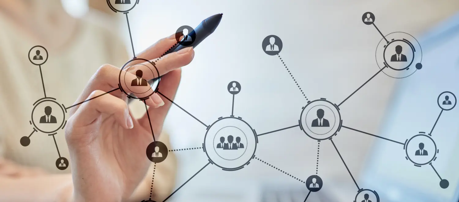 aufgemaltes Organigramm an einer Glasscheibe. Dahinter steht eine Frau mit einem schwarzen Stift in der Hand.